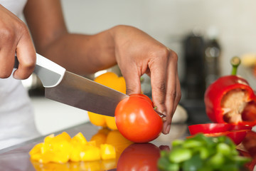 African  American womans hand slicing a tomatoe