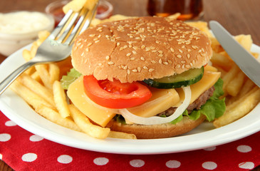 Tasty cheeseburger with fried potatoes, on bright background