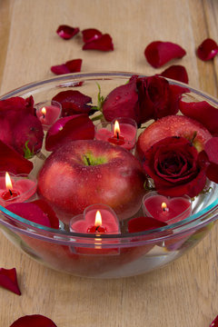 Apple with rose petals and heart candles in glass bowl