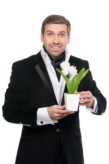Handsome surprised stylysh man presenting flower. Isolated over