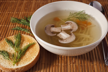 vermicelli soup and field mushrooms in a plate on a straw napkin