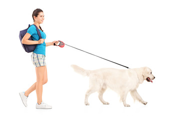 Full length portrait of a female student walking her dog