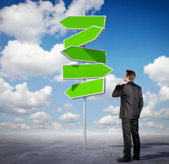 Businessman looking at an arrow sign
