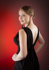Fototapeta premium Beautiful girl in black dress on red background