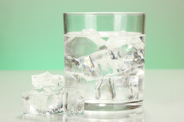 Ice cubes in glass on light green background