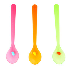 Plastic spoons with color pills, isolated on white