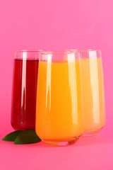 Glasses of juise and leafs on pink background