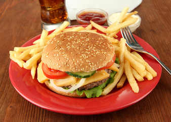 Tasty cheeseburger with fried potatoes and cold drink,