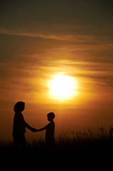 Naklejka na ściany i meble Silhouette of mother and child with sunset background