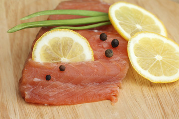 salmon fillet with lemon and spices on wooden board, close-up