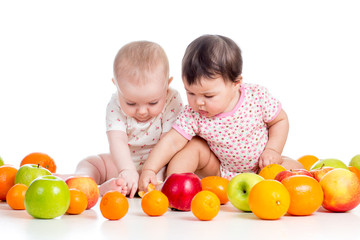 Fototapeta na wymiar Funny niemowląt dziewczyny jedzenie zdrowej żywności owoce samodzielnie na białym tle