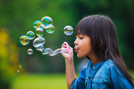 Asian little girl is blowing a soap bubbles