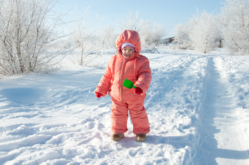 Fototapeta na wymiar baby in pink overalls on background of a winter forest