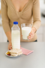 Closeup on young woman holding out glass of milk