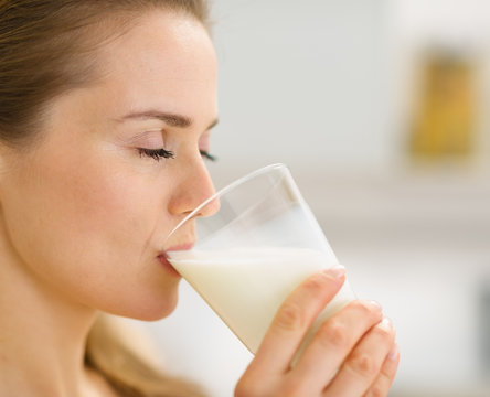 Closeup on young woman drinking milk