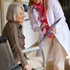 Krankenschwester bittet Seniorin um Unterschrift - obrazy, fototapety, plakaty