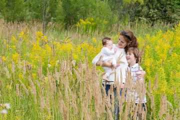Naklejka na ściany i meble Young attractive mother with two kids in a yellow flower field