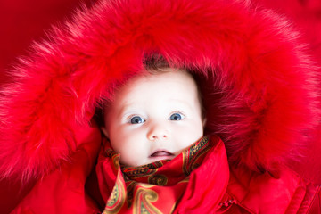 Little baby girl in a red fur jacket
