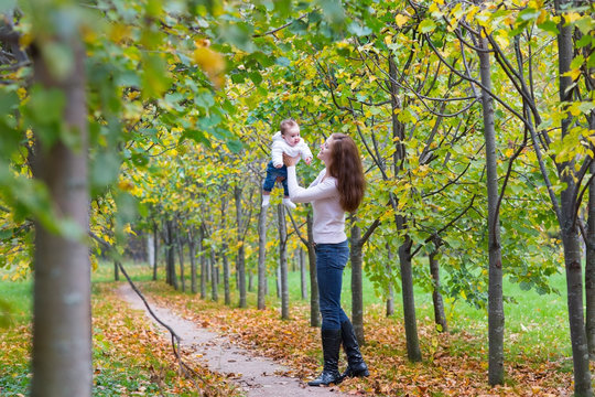 Young beautiful woman playing with her baby in a park