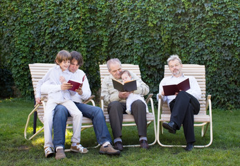 Four generations relaxing in the garden, reading books