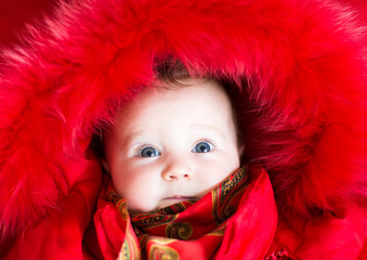 Little baby girl in a red fur jacket