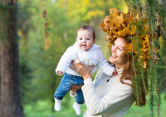Mother holding baby girl in forest with maple leaf wreath
