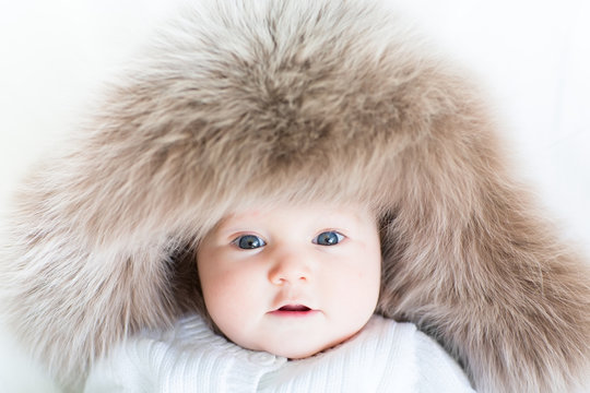 Adorable baby with blue eyes wearing a big fur hat