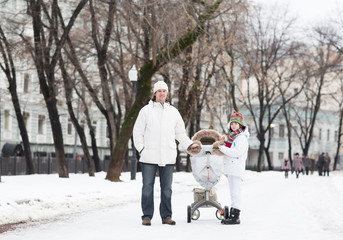 Fototapeta na wymiar Man, son and baby in stroller walking in snowy park