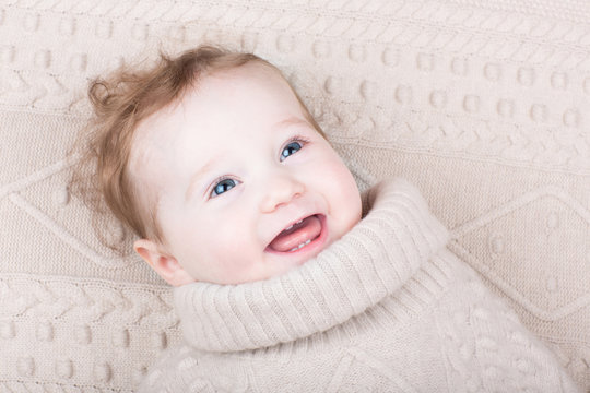 Cute gunny baby girl in a knitted sweater on a knitted blanket