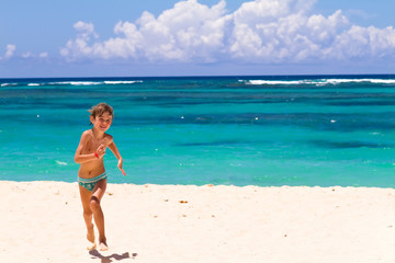Fototapeta na wymiar Boy running on a tropical beach with turquoise water