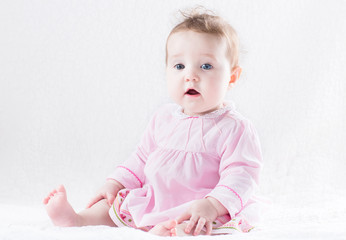 Beautiful baby girl in a pink dress on a white background
