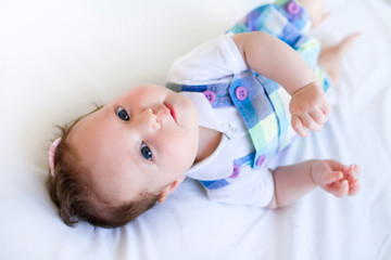 Adorable brunette baby girl in purple overalls