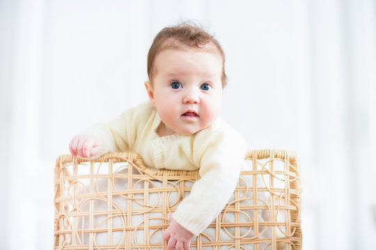 Cute curious baby watching out of a laundry basket