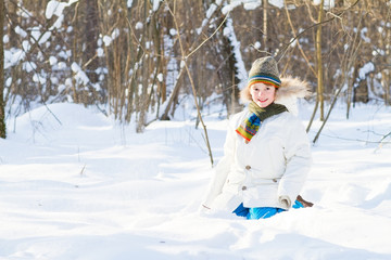 Happy child playing in a snow field on a sunny winter day