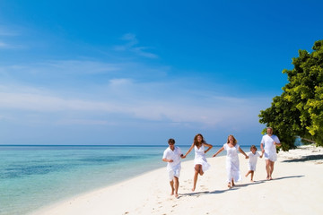 Family celebrating running on beautiful tropical beach