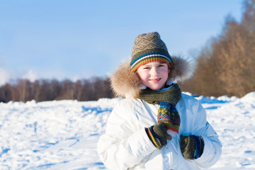 Fototapeta premium Smiling child on a walk in a snowy winter forest