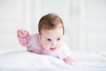 Cute funny baby girl in a pink cardigan trying to crawl