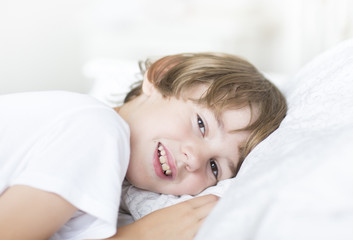 Fototapeta na wymiar Boy with brown eyes lying on a white pillow