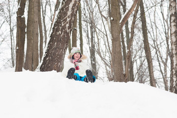 Fototapeta na wymiar Happy child sledging from a snowy hill