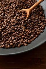 Black wok pan with coffee beans on wooden table, close up