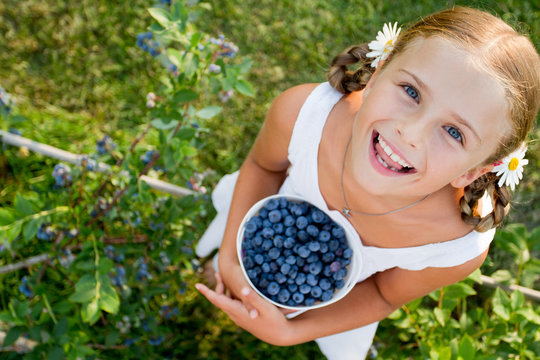 Blueberries - Girl with  ripe blueberries in the garden