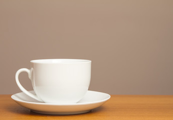 White cup and saucer on wooden table