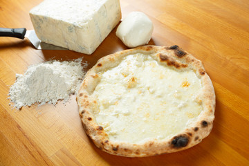 Italian Pizza, ingredients in the background on a wood table