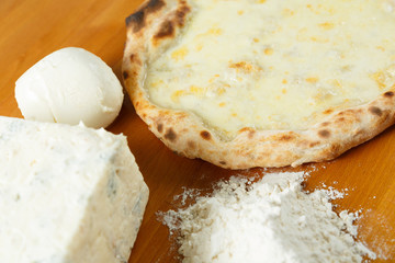 Italian Pizza, ingredients in the background on a wood table