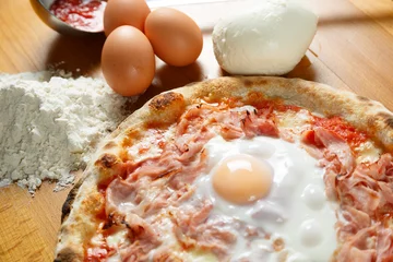Photo sur Plexiglas Pizzeria Pizza italienne typique, ingrédients en arrière-plan sur table en bois