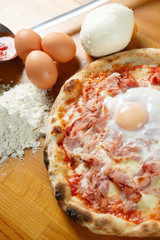 Typical Italian Pizza, ingredients in background on wood table
