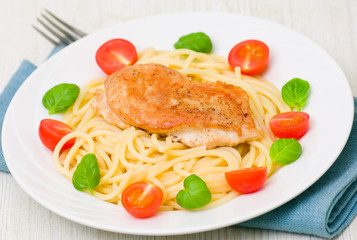 chicken breast with pasta, garnished with tomato and fresh basil