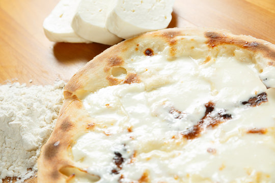Italian Pizza, ingredients in the background on a wood table