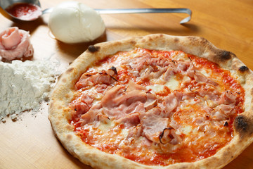 Typical Italian Pizza, ingredients in background on wood table