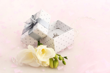 Beautiful box with wedding ring and flower on pink background